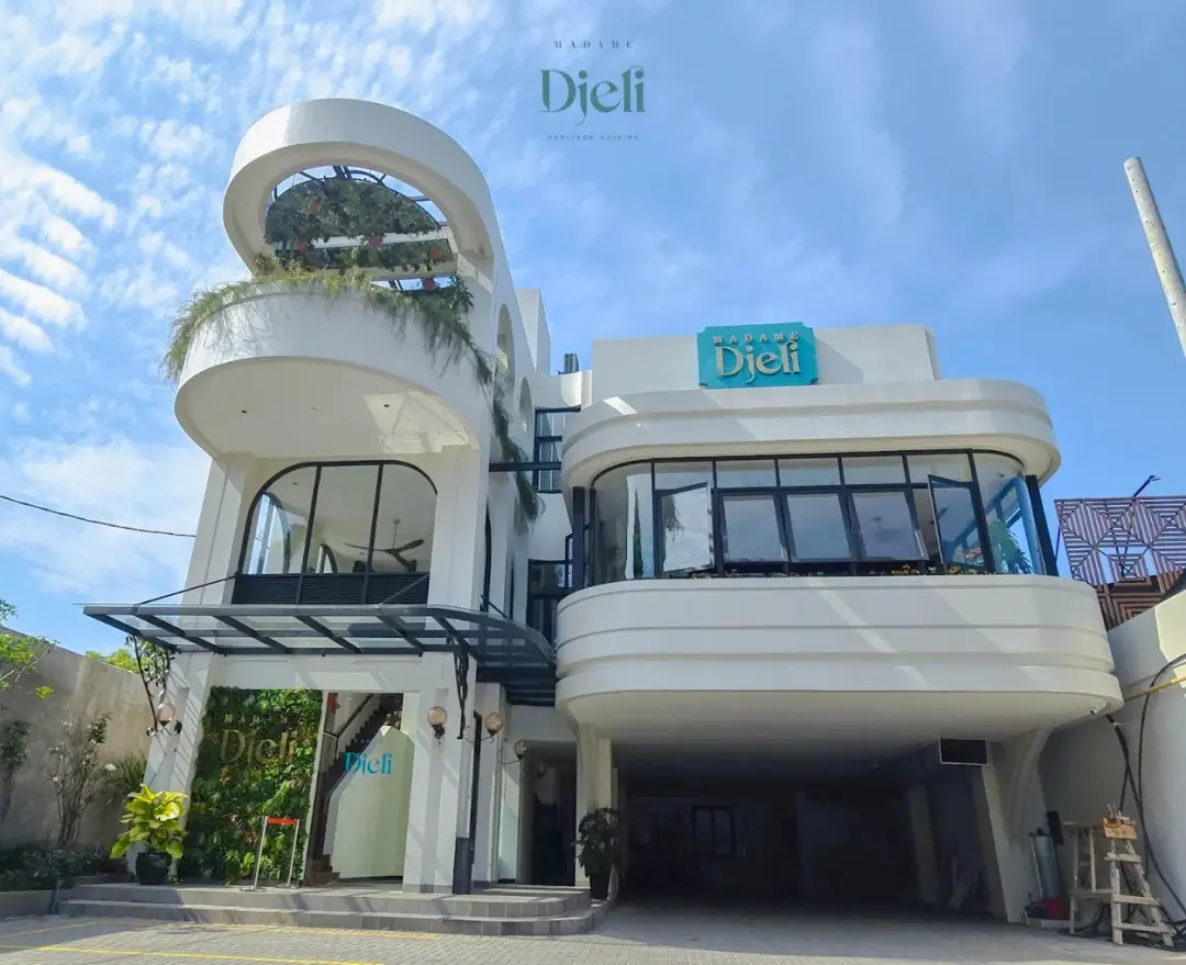 Tampilan eksterior atau fasad bangunan arsitektur modern berwarna putih dari Restoran Madame Djeli di Bogor, lokasi proyek di mana Permata Furni menjadi supplier custom furniture jati.