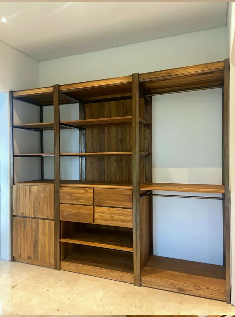 Sebuah unit wardrobe custom bergaya industrial, dibuat dari kombinasi kayu jati reclaimed dan rangka besi gelap, menampilkan rak terbuka, laci-laci, dan area gantungan baju.