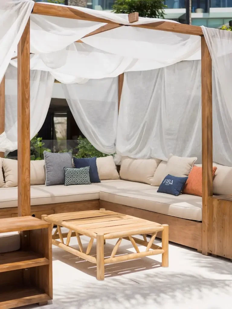 Cabana outdoor mewah dari kayu jati reclaimed dengan sofa L-sectional yang nyaman dan meja kopi, bagian dari proyek furnitur kustom Permata Furni untuk Fira Beach Club di Phuket.