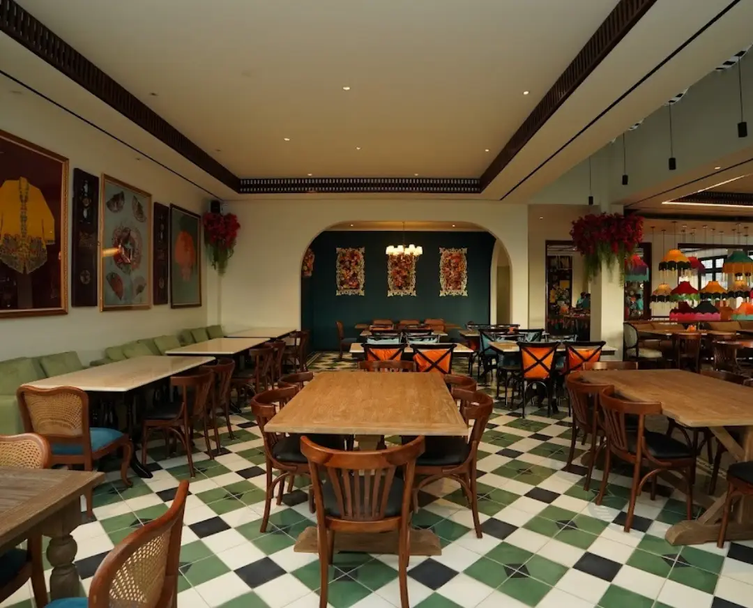 Suasana interior Restoran Madame Djeli Bogor yang elegan, menampilkan set custom furniture jati dari Permata Furni berupa meja makan kayu solid dan kursi-kursi model klasik di atas lantai keramik hijau-putih.